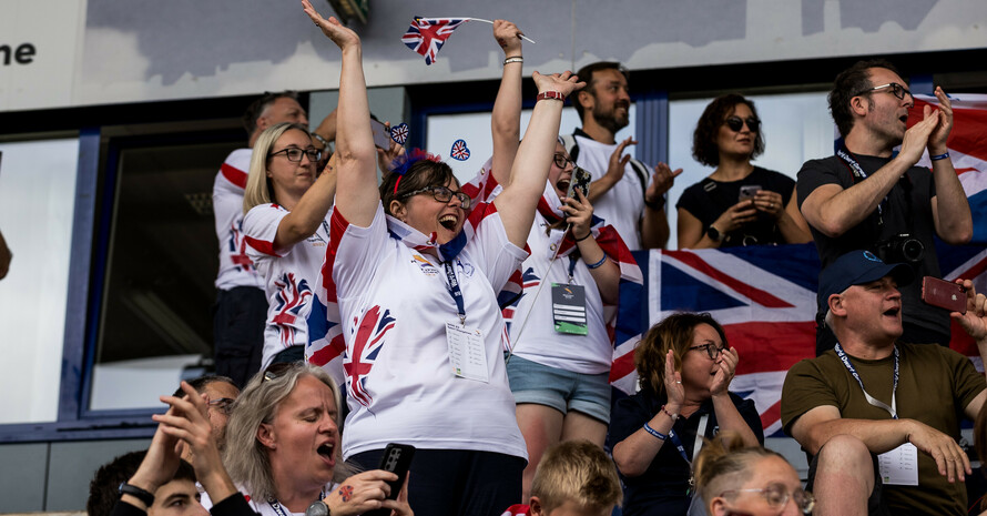 Die Fans der britischen Nationalmannschaft jubeln stehend auf der Tribüne mit Flaggen und weiteren Accesoires
