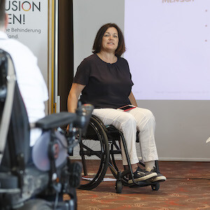 Eine Frau im Rollstuhl hält eine Präsentation.