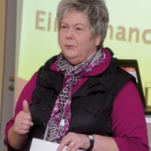 Marion Böhm hält einen Vortrag. Im Hintergrund ist eine Power-Point-Präsentation zu sehen.